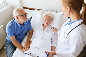 Patient in hospital bed talking to doctor